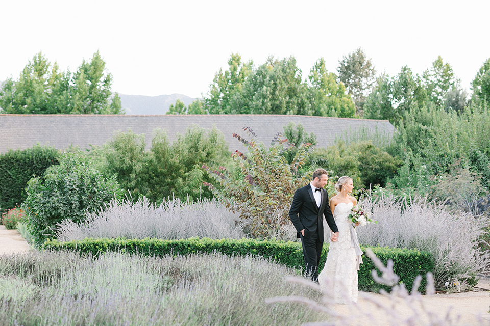 Santa-barbara-outdoor-wedding-at-kestrel-park-bride-and-groom-holding-hands-walking-with-bouquet