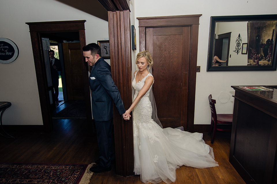 Orange-county-wedding-at-the-hamilton-oaks-winery-bride-and-groom-holding-hands-behind-wall