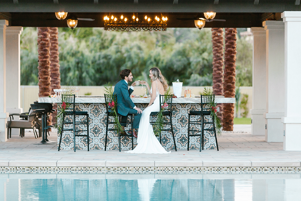 Palm-springs-wedding-shoot-at-old-polo-estate-bride-and-groom-sitting-holding-drinks