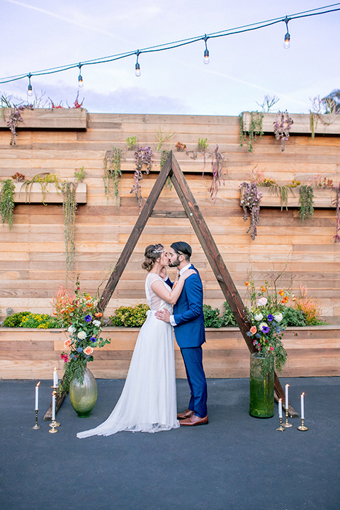 lot-8-colorful-romance-shoot-ceremony-space-bride-in-a-bohemian-style-dress-with-capped-sleeves-a-headpeice-and-hair-in-a-bohemian-braid-groom-in-a-cobalt-suit-with-orange-florals-and-a-bolo-tie