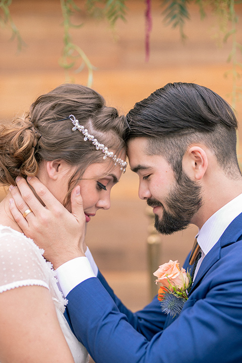 lot-8-colorful-romance-shoot-close-up-of-bride-and-groom-heads-touching-bride-in-a-bohemian-style-dress-with-capped-sleeves-a-headpeice-and-hair-in-a-bohemian-braid-groom-in-a-cobalt-suit-with-orange-florals-and-a-bolo-tie