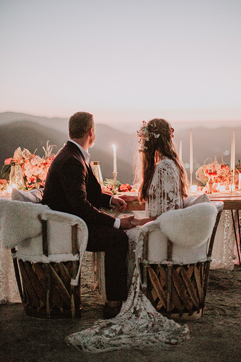 hey-babe-ranch-bride-and-groom-looking-into-the-distance-back-to-camera-bride-looking-at-him-bride-in-a-bohemian-gown-with-lace-and-fringe-detailing-and-hair-in-a-loose-wave-groom-in-a-burgundy-tuxedo-with-black-satin-truim-and-his-tie-undone-for-a-relaxed-look