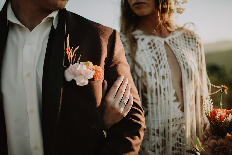 hey-babe-ranch-close-up-of-bride-and-groom-bride-in-a-bohemian-gown-with-lace-and-fringe-detailing-and-hair-in-a-loose-wave-groom-in-a-burgundy-tuxedo-with-black-satin-truim-and-his-tie-undone-for-a-relaxed-look