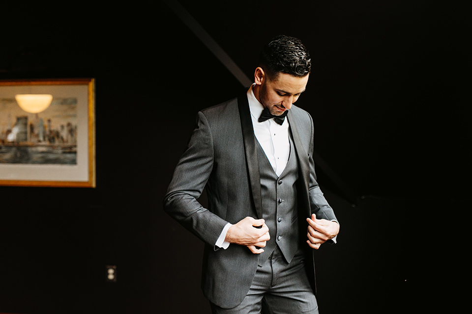 The-Mansion-at-Natirar-groom-putting-on-jacket-groom-in-a-grey-tuxedo-with-black-trim-and-a-black-bowtie