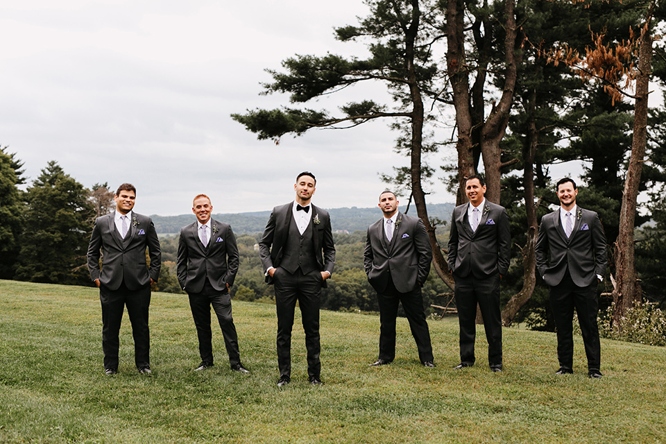 the-mansion-at-natirar-groomsmen-outside-groom-in-a-grey-tuxedo-with-black-trim-and-a-black-bowtie-groomsmen-in-grey-tuxedos-with-purple-ties