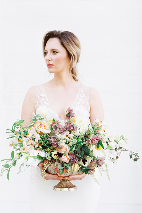 Taylor-Grady-House-shoot-bride-holding-flowers-bride-in-a-fit-and-flar-silk-gown-with-an-open-back-detail-and-hair-in-a-loose-bun-holding-a-big-bouquet-of-white-and-muted-toned-flowers