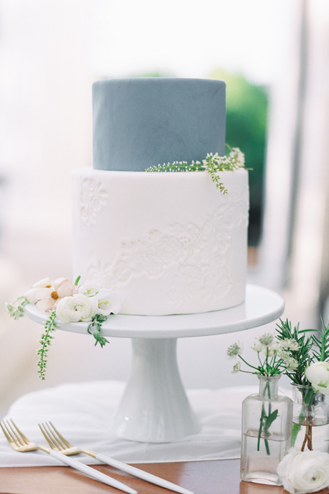 Taylor-Grady-House-shoot-cake-two-tier-cake-with-bottom-layer-is-a-clean-white-and-the-top-a-dusty-blue-shade-with-white-and-green-minimal-flowers-on-it