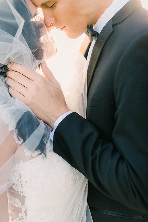 callaway-winery-shoot-bride-and-groom-close-up-with-veil-over-her-face-bride-wearing-a-fitted-dress-with-straps-and-tulle-and-lace-detailing-while-the-groom-wore-a-traditional-black-tuxedo-with a-black-bowtie