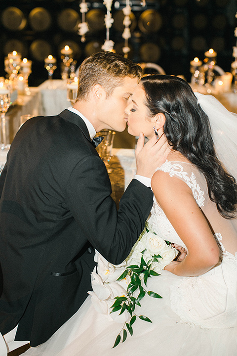 callaway-winery-shoot-bride-and-groom-kissing-bride-wearing-a-fitted-dress-with-straps-and-tulle-and-lace-detailing-while-the-groom-wore-a-traditional-black-tuxedo-with a-black-bowtie