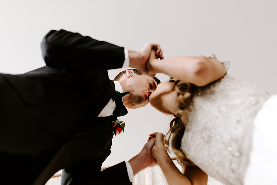 huntington-bay-club-shoot-bride-alone-looking-over-her-shoulder-bride-wearing-a-flowing-gown-with-a-beaded-bodice-and-ca-sleeves-groom-wearing-a-black-suit-with-a-green-velvet-bow-tie