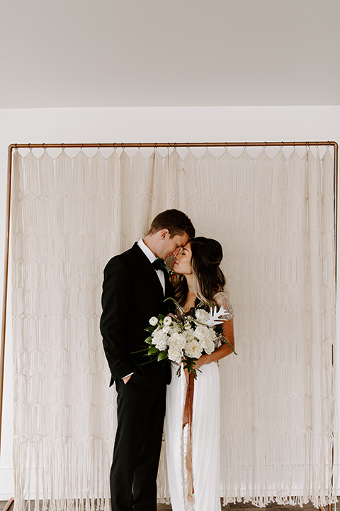 huntington-bay-club-shoot-bride-and-groom-ceremony-space-bride-wearing-a-flowing-dress-with-a-beaded-bodice-and-sleeves-groom-wearing-a-black-suit-with-a-green-velvet-bow-tie