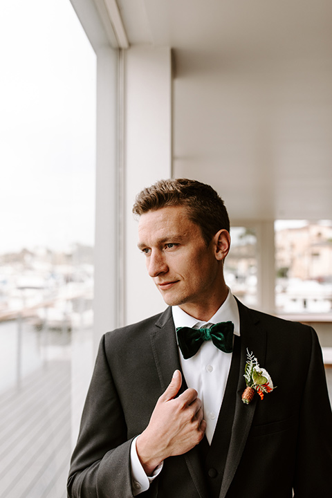 huntington-bay-club-shoot-groom-alone-groom-wearing-a-black-suit-with-a-green-velvet-bow-tie