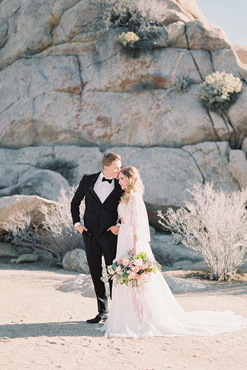 Joshua-tree-wedding-shoot-at-the-ruin-venue-bride-and-groom-holding-hands-and-kissing