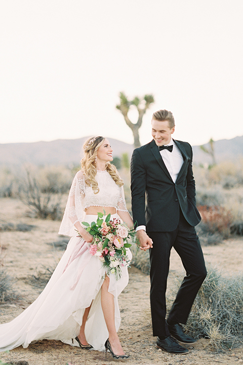 Joshua-tree-wedding-shoot-at-the-ruin-venue-bride-and-groom-holding-hands-and-walking-smiling