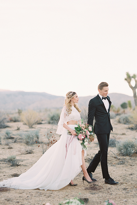 Joshua-tree-wedding-shoot-at-the-ruin-venue-bride-and-groom-holding-hands-and-walking