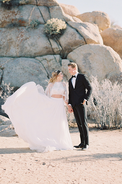 Joshua-tree-wedding-shoot-at-the-ruin-venue-bride-and-groom-holding-hands-bride-holding-dress