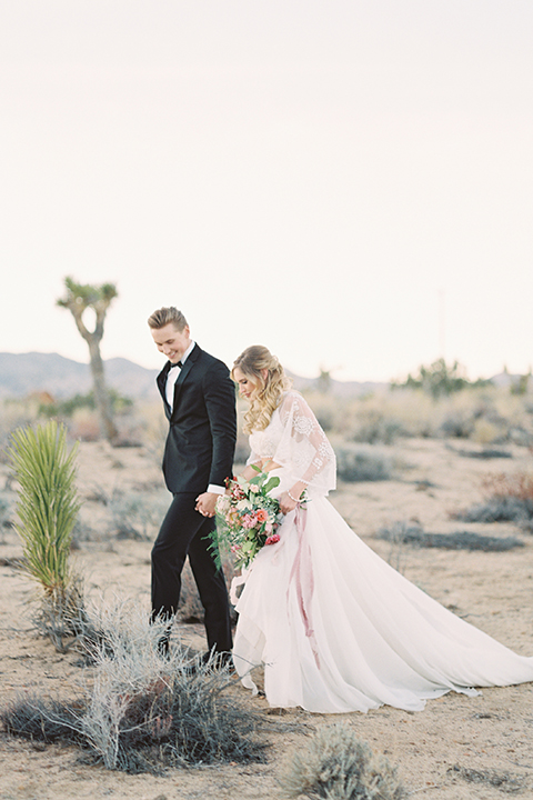 Joshua-tree-wedding-shoot-at-the-ruin-venue-bride-and-groom-standing-holding-hands-and-walking