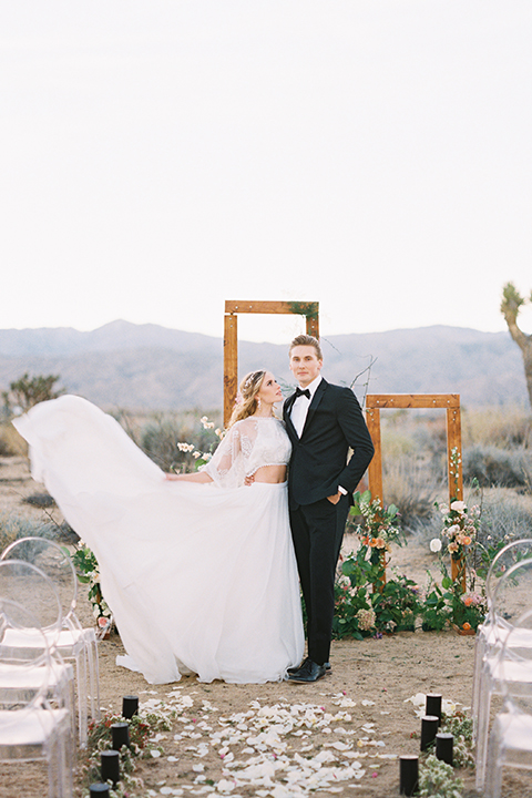 Joshua-tree-wedding-shoot-at-the-ruin-venue-ceremony-bride-and-groom-holding-dress