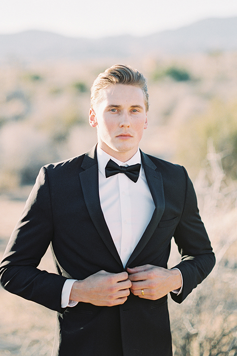 Joshua-tree-wedding-shoot-at-the-ruin-venue-groom-black-tuxedo-holding-coat-buttoning