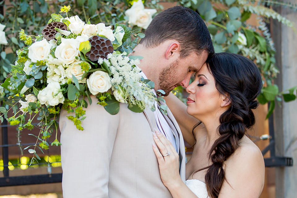 lot-8-bride-and-groom-touching-heads-eyes-closed-bride-wearing-a-white-strapless-bridal-gown-with-lace-embellishments-hair-in-a-loose-braid-groom-wearing-a-light-grey-suit-with-a-silver-tie 