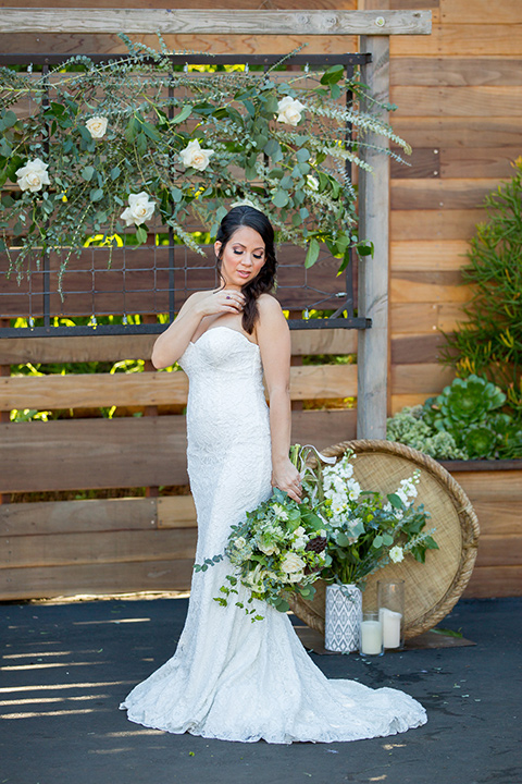 lot-8-bride-looking-over-her-shoulder-bride-wearing-a-white-strapless-bridal-gown-with-lace-embellishments-hair-in-a-loose-braid-holding-a-big-floral-bouquet