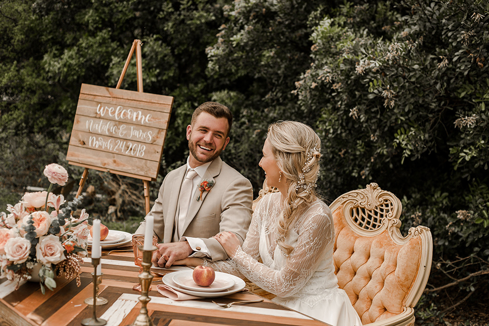 Texas-peaches-and-cream-wedding-shoot-at-carola-horse-ranch-bride-and-groom-sitting-at-table