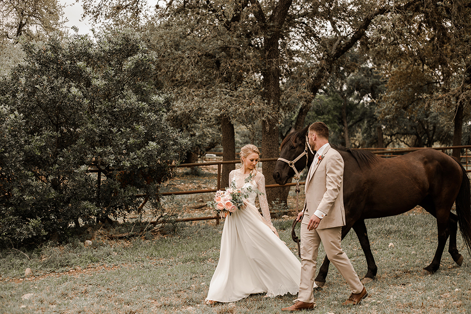 Texas-peaches-and-cream-wedding-shoot-at-carola-horse-ranch-bride-and-groom-walking-with-horse