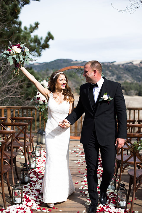 sacred-mountain-shoot-bride-and-groom-walking-towards-camera-with-flowers-raised