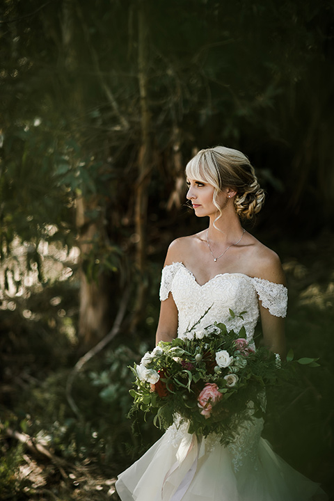 saddle-peak-bride-alone-bride-in-an-off-the-shoulder-gown-with-lace-detailing-and-hair-up-in-a-bun