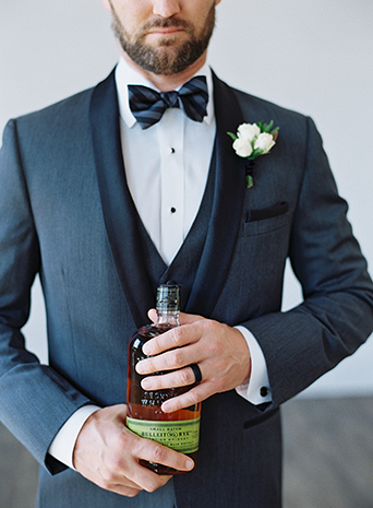 Same-sex-industrial-wedding-at-the-1912-groom-charcoal-tuxedo-close-up-holding-drink