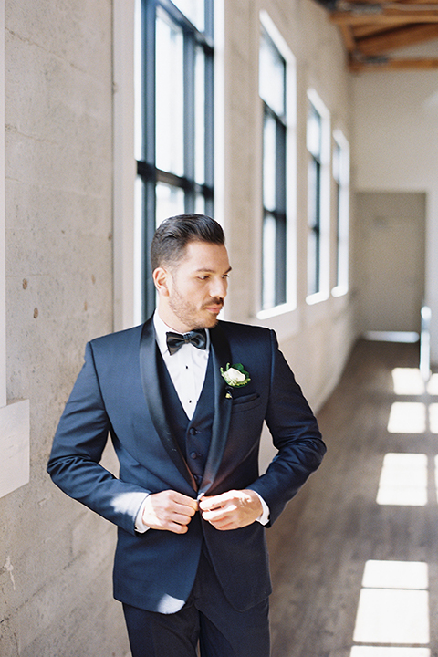 Same-sex-industrial-wedding-at-the-1912-groom-navy-tuxedo-buttoning-coat