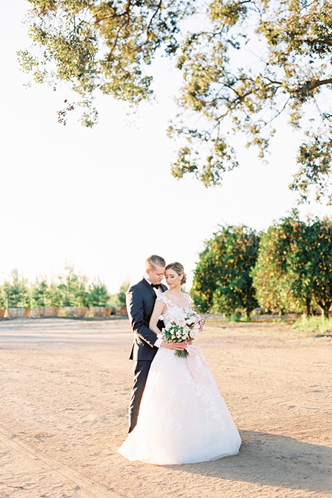 Southern-california-outdoor-wedding-at-the-orange-grove-bride-and-groom-hugging-holding-bouquet-far-away