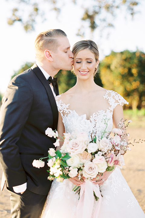 Southern-california-outdoor-wedding-at-the-orange-grove-bride-and-groom-hugging-holding-bouquet-kissing-close-up