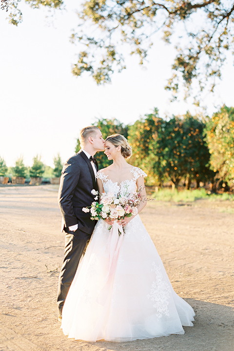 Southern-california-outdoor-wedding-at-the-orange-grove-bride-and-groom-hugging-holding-bouquet-kissing