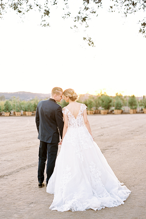 Southern-california-outdoor-wedding-at-the-orange-grove-bride-and-groom-standing-holding-hands-back