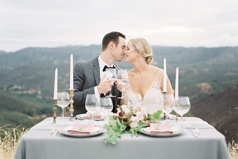 mountain-elopement-shoot-bride-and-groom-at-sweetheart-table-groom-in-a-grey-tuxedo-with-a-black-bowtie