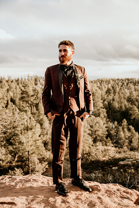 Arizona-Elopement-Shoot-groom-standing-in-a-burgundy-shawl-lapel-tuxedo-with-a-black-shirt-and-bow-tie