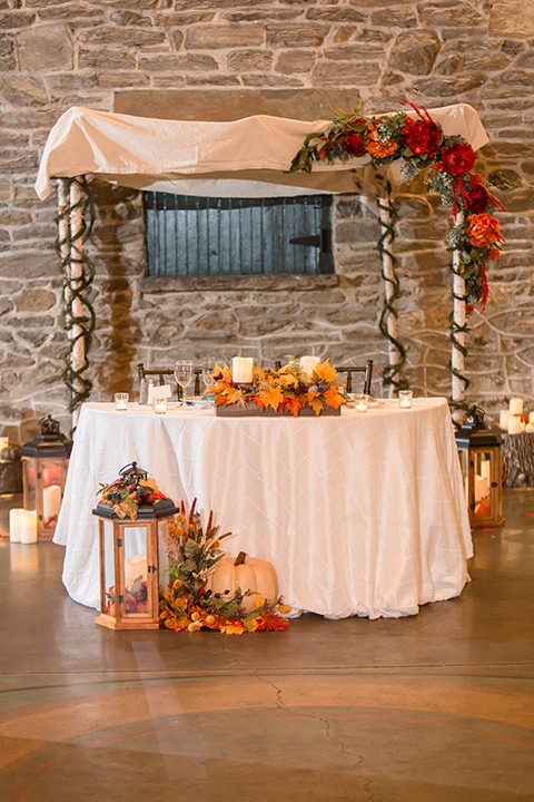 indoor décor with fall vibes with colorful leaves and pumpkins at sweetheart table