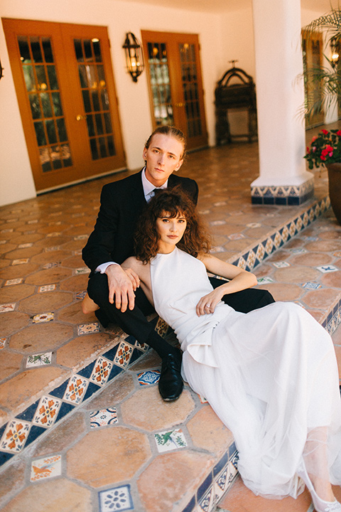 Rancho-las-lomas-blue-shoot-bride-and-groom-sitting-on-the-ground-the-bride-wore-a-flowing-white-gown-and-a-halter-neckline-and-the-groom-wore-a-black-suit-with-a-black-long-tie