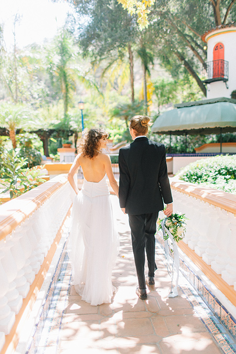 Rancho-las-lomas-blue-shoot-bride-and-groom-walking-away-the-bride-wore-a-flowing-white-gown-and-a-halter-neckline-and-the-groom-wore-a-black-suit-with-a-black-long-tie