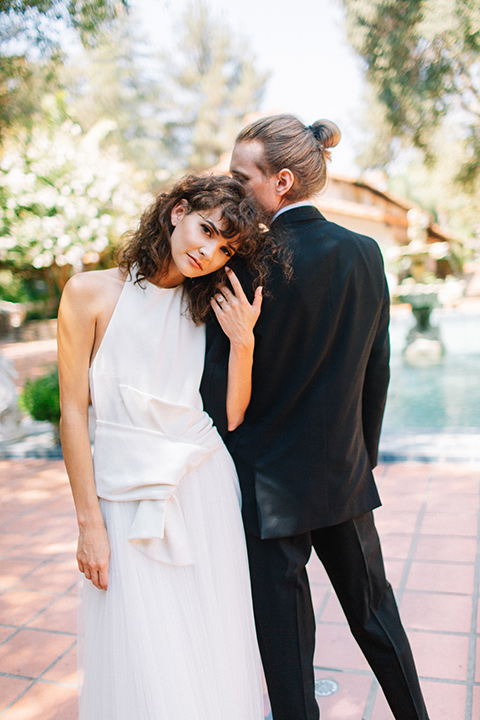 Rancho-las-lomas-blue-shoot-bride-facing-camera-groom-facing-away-from-camera-the-bride-wore-a-white-dress-with-a-halter-neckline-and-black-notch-lapel-suit-and-black-long-tie