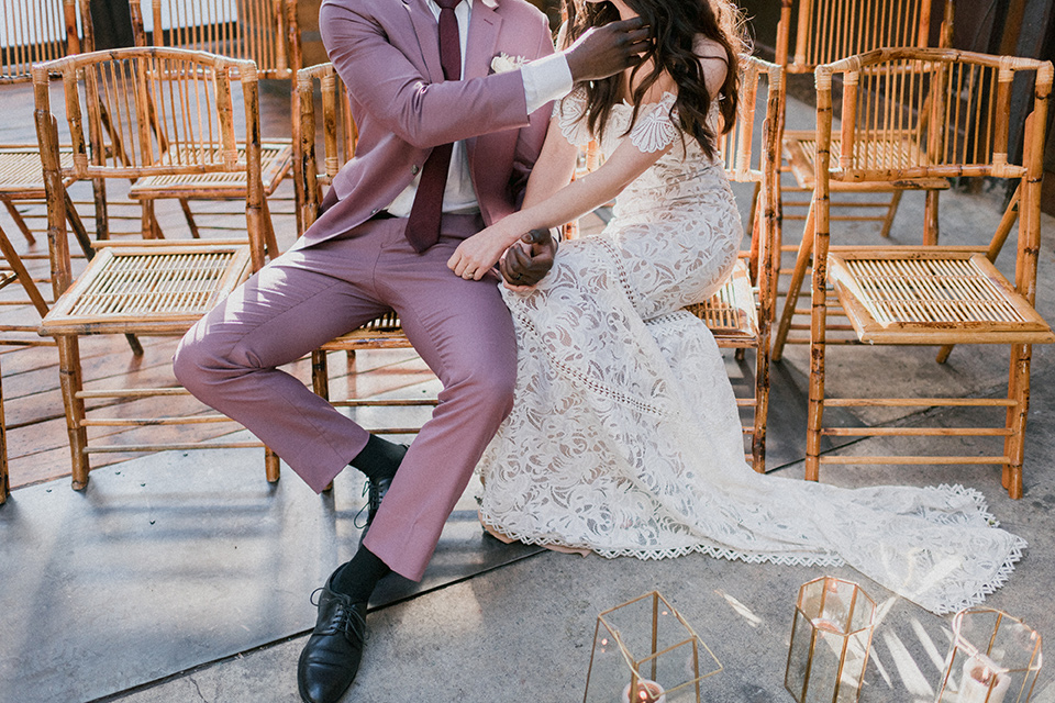 Brooklyn-Shoot-bride-and-groom-close-up-in-chairs-groom-in-a-rose-pink-suit-with-brown-shoes-the-bride-in-a-lace-boho-style-gown
