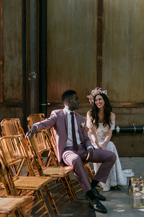 Brooklyn-Shoot-bride-and-groom-in-chairs-bride-in-a-bohemian-style-gown-and-groom-in-a-rose-pink-suit-with-brown-shoes-and-burgundy-long-tie