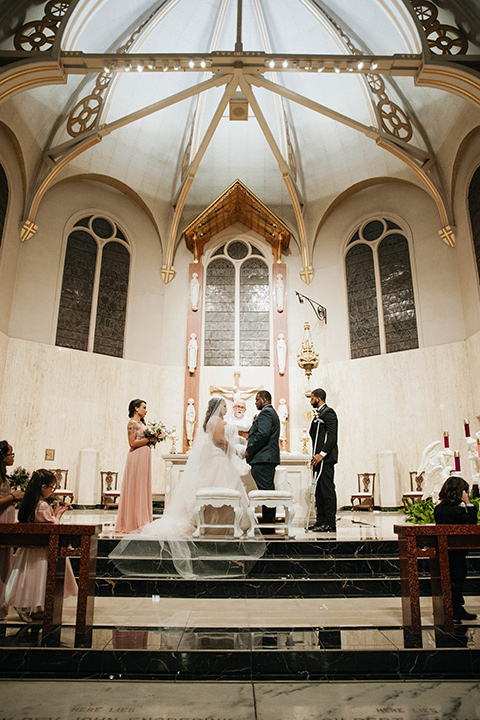 Fete-Venue-New-Orleans-Wedding-bride-and-groom-at-ceremony-bride-in-a-strapless-ball-gown-groom-in-a-navy-tuxedo-with-a-black-shawl-lapel