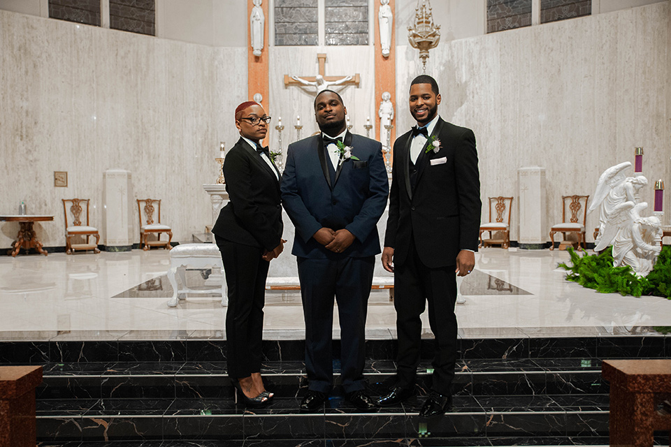 Fete-Venue-New-Orleans-Wedding-groom-in-navy-tuxedo-with-a-shawl-lapel-and-groomsman-and-groomswoman-in-black-tuxedos