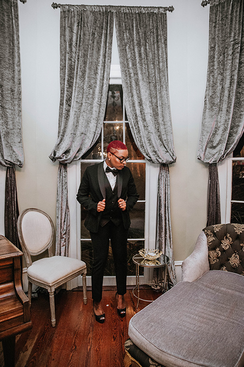 Fete-Venue-New-Orleans-Wedding-groomswoman-buttoning-jacket-of-black-tuxedo