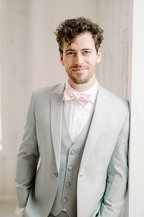  groom in a light grey suit with pink bow tie