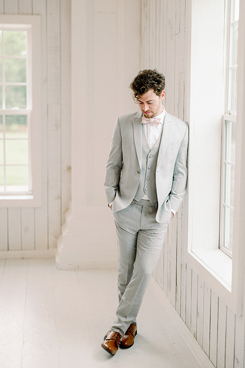  groom in a light grey suit with pink bow tie