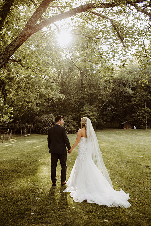 Horse-Range-Vista-bride-and-groom-walking-away-bride-in-a-lace-mermaid-gown-with-a-sweetheart-neckline-groom-in-a-green-suit-with-a-floral-tie