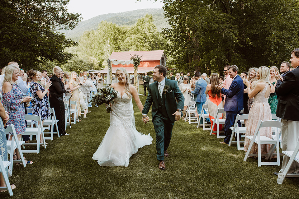 Horse-Range-Vista-end-of-ceremony-bride-in-a-lace-mermaid-gown-with-a-long-veil-groom-in-a-green-suit-with-a-floral-tie